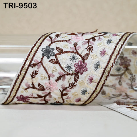a decorative fabric with a floral pattern, including various shades of pink, purple, and brown. The fabric appears to be a decorative trim or border, with intricate embroidered designs.