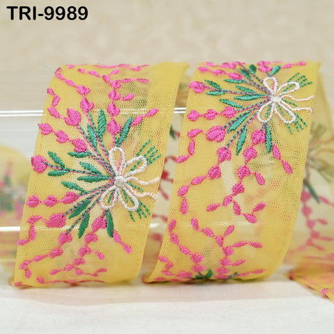 two pieces of yellow fabric with intricate floral embroidery in shades of pink and green.