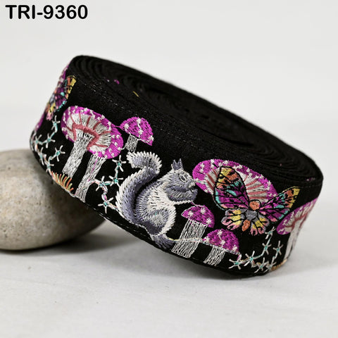 A black fabric with a colorful, whimsical design of mushrooms, butterflies, and a squirrel.