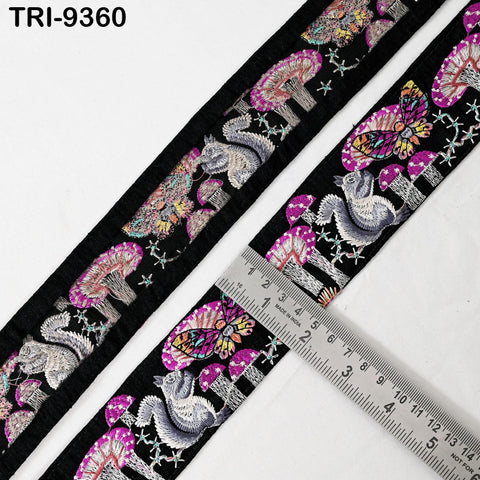 a decorative fabric with a repeating pattern of colorful mushrooms and butterflies. A ruler is placed on the fabric, indicating the size of the pattern.