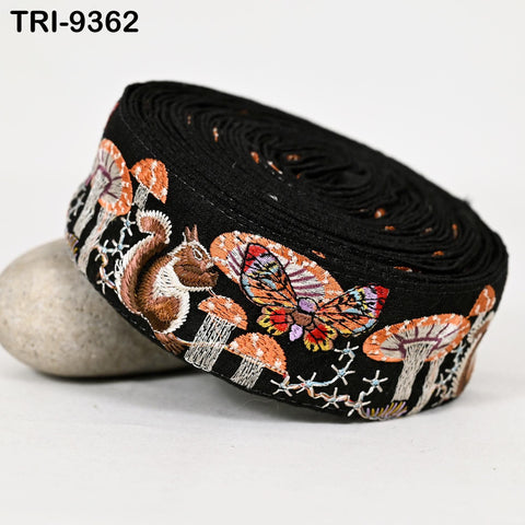 A black fabric with a colorful butterfly and mushroom design, along with a squirrel, is shown in the image.