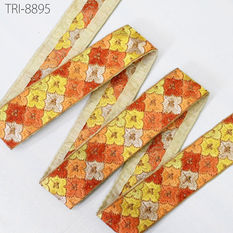 a decorative fabric with a repeating pattern of orange and yellow flowers, arranged in a zigzag pattern.