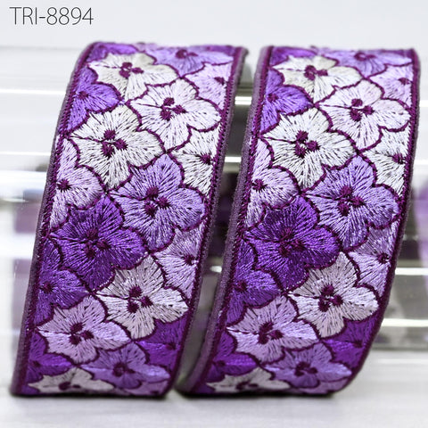 two decorative fabric pieces with a floral pattern in shades of purple and white.
