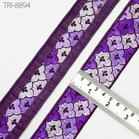 a close-up view of a decorative ribbon with a floral pattern in shades of purple and white. A ruler is placed next to the ribbon, indicating its size.