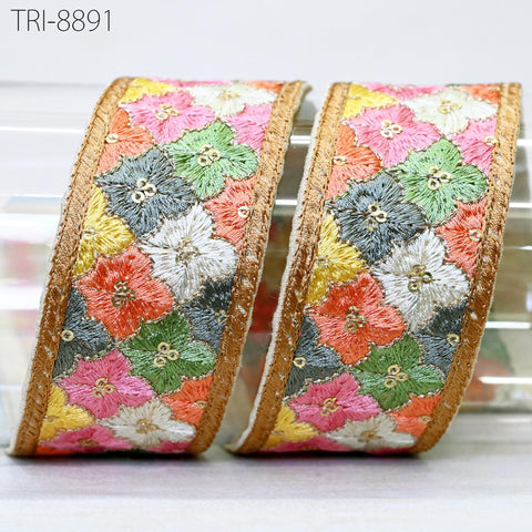 two decorative fabric ribbons with a floral pattern in various colors, including pink, green, yellow, and orange. The ribbons have a gold border and appear to be made of embroidered material.