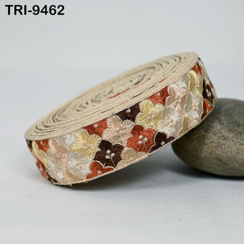 A beige, circular fabric with a floral pattern in shades of brown and orange, resting on a gray rock.
