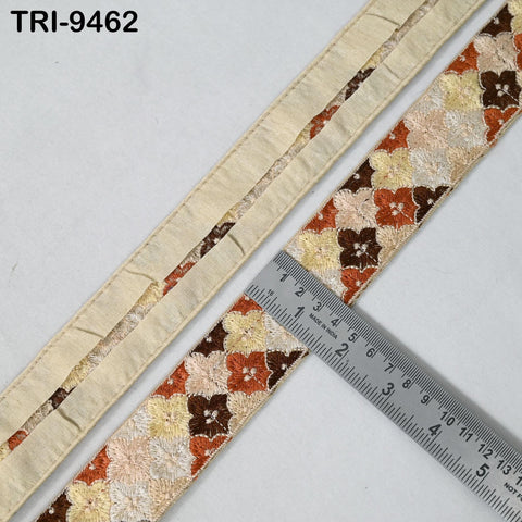 a close-up view of a decorative fabric with a floral pattern, placed on a white surface. A ruler is placed next to the fabric, indicating its size.