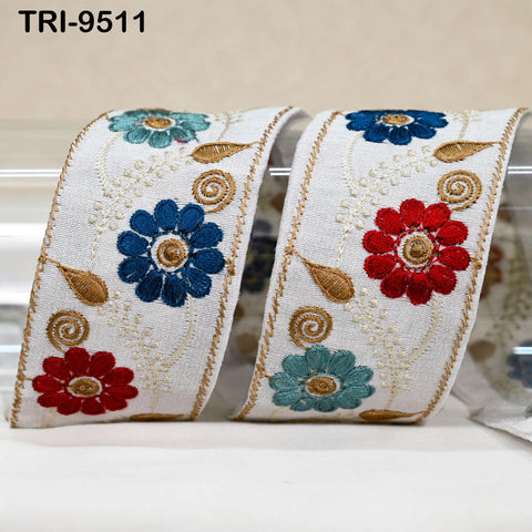 two decorative fabric pieces with intricate floral embroidery in various colors, including blue, red, and green, arranged in a symmetrical pattern.