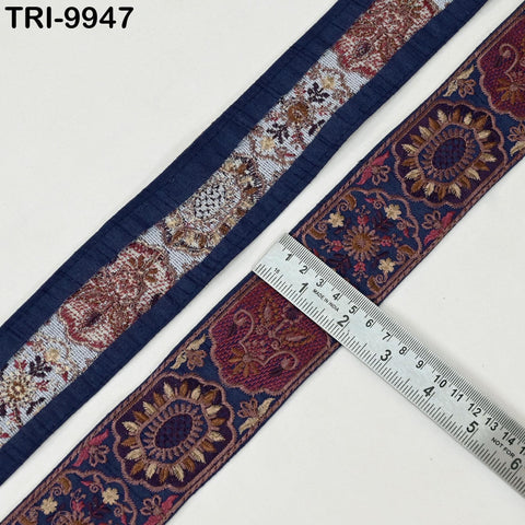 a close-up view of a decorative fabric with a floral pattern, placed next to a ruler for size comparison.
