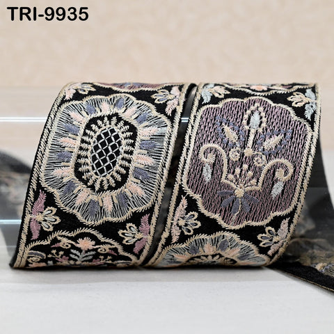 a decorative fabric with intricate floral and geometric patterns in shades of black, purple, and pink. The fabric appears to be a decorative textile, possibly used for embellishment or as a decorative element.