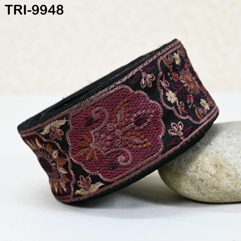 a decorative band with a floral pattern in shades of red and black, resting on a white surface.
