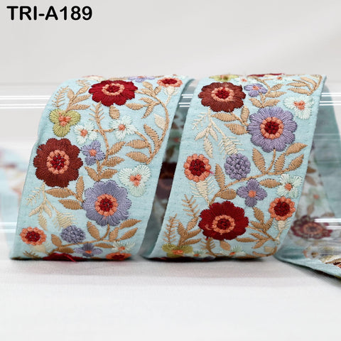 a close-up view of a decorative fabric with a floral pattern. The fabric appears to be light blue in color and features a variety of colorful flowers and leaves, creating a visually appealing and intricate design.