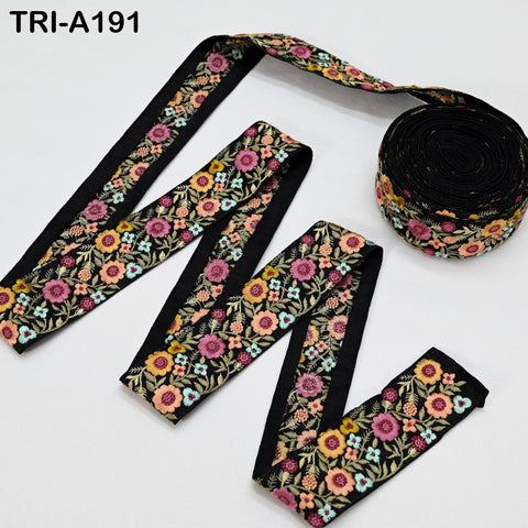 a spool of embroidered fabric with a floral pattern, and a spool of black thread with a floral pattern.