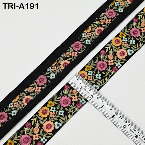 a close-up view of a decorative fabric with a floral pattern, featuring a black border and a ruler for size reference.