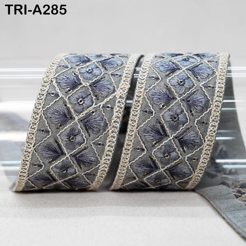 a decorative fabric with a repeating pattern of blue and gray floral designs, featuring a lace-like border.
