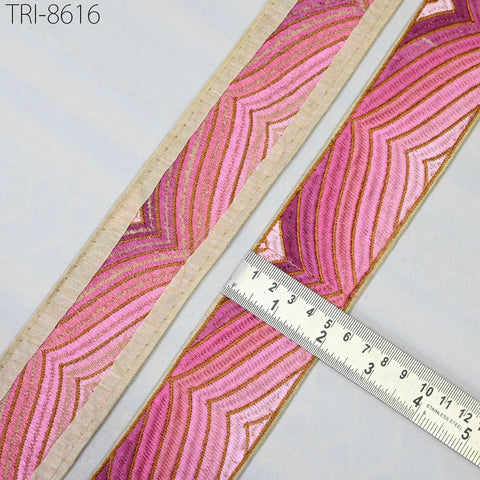 a close-up view of a decorative fabric with a pink and gold striped pattern. A ruler is placed next to the fabric, indicating the size of the fabric.