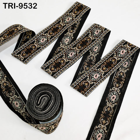 a collection of decorative black and gold embroidered fabric pieces, including a roll of the same material.