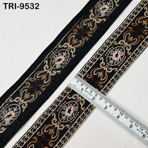 a close-up view of a decorative black fabric with intricate floral embroidery. A ruler is placed on top of the fabric, indicating the size of the fabric.