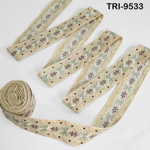 a collection of beige and green embroidered ribbons arranged on a white background.