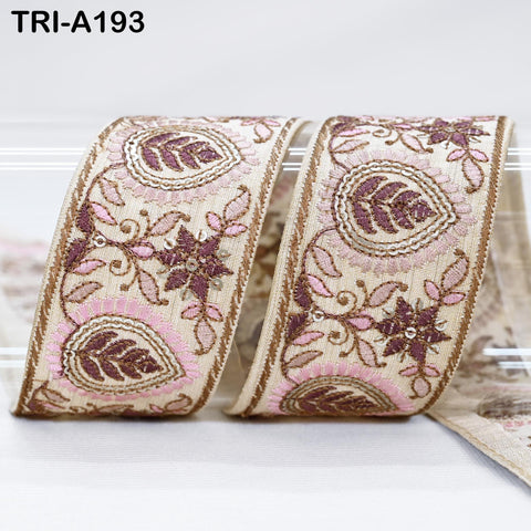 a decorative ribbon with a floral pattern in shades of pink and brown. The ribbon is rolled up and placed on a white surface.