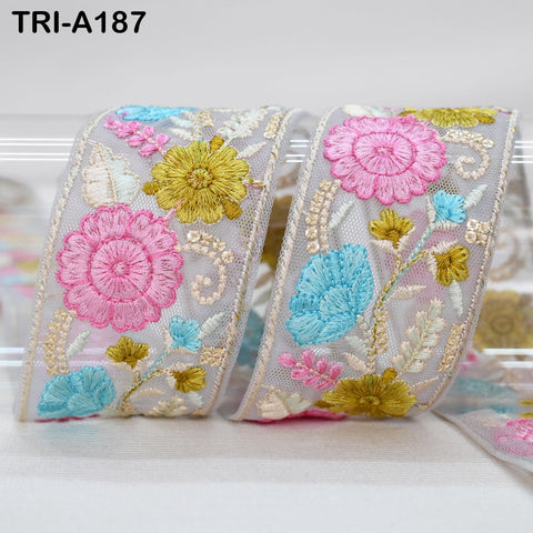 a decorative ribbon with a floral pattern, including pink, blue, and yellow flowers, as well as leaves and stems. The ribbon appears to be made of a light-colored material, possibly lace or fabric.