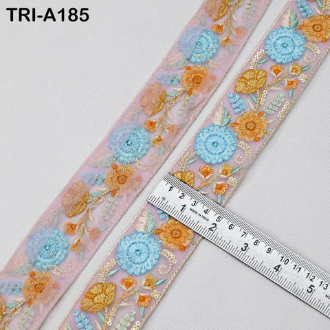 a decorative fabric with a floral pattern, including blue and orange flowers, and a ruler placed on top of it.