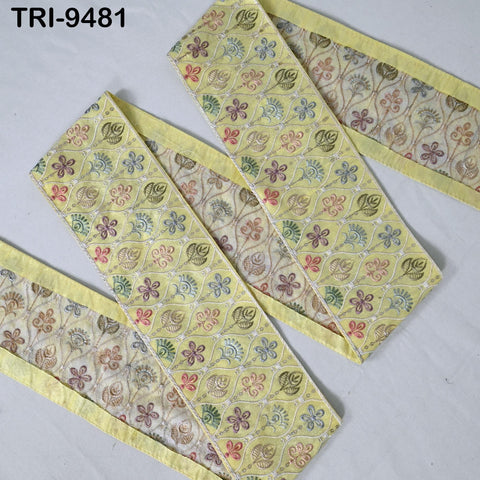 a collection of fabric pieces with a yellow and green floral pattern. The fabric appears to be a decorative trim or border, with a repeating pattern of flowers and leaves. The fabric pieces are arranged on a white background, creating a visually appealing contrast.