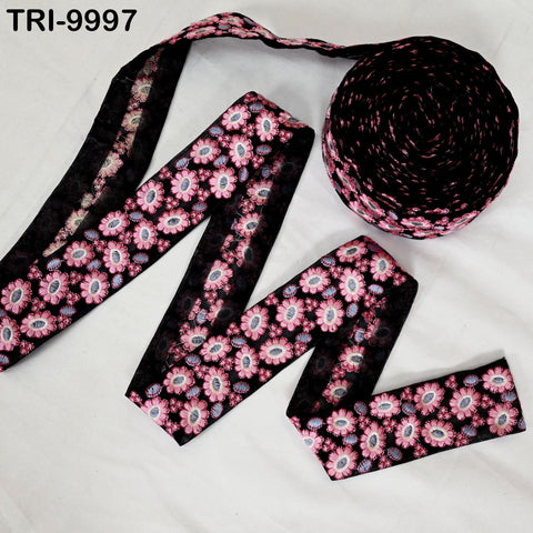 a spool of black and pink floral embroidery thread, along with a spool of the same thread, arranged on a white surface.