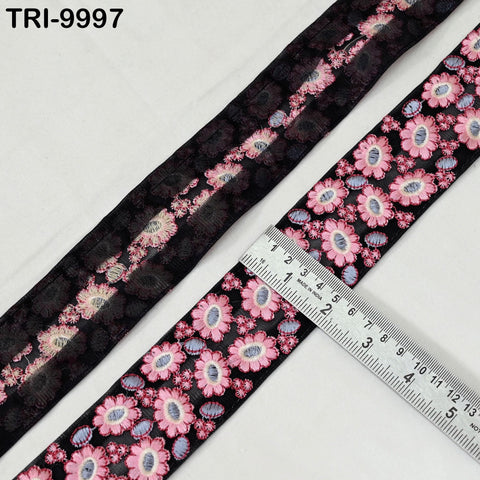 a black and pink floral patterned fabric, with a ruler placed on top of it to measure its length.