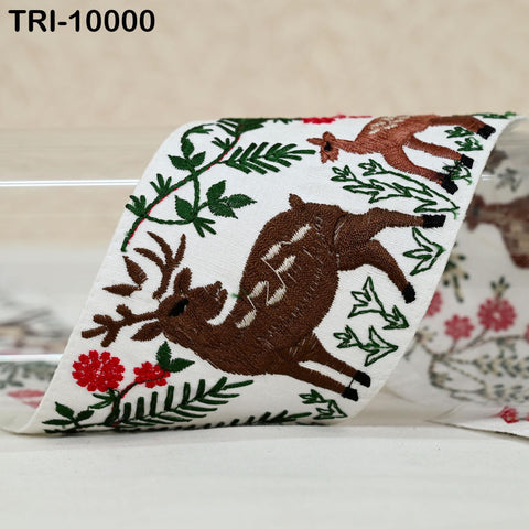 a close-up of a decorative fabric with a brown deer and green leaves, along with red flowers.
