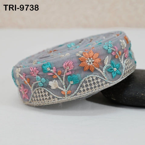 A decorative gray fabric with a floral pattern, featuring various shades of blue, pink, and orange flowers, as well as green leaves and stems.