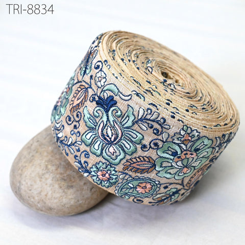 a decorative fabric with a floral pattern, including blue, green, and pink colors, and it is rolled up and placed on a white surface.