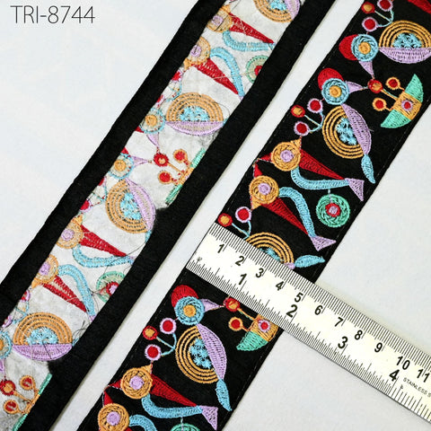 a close-up view of a colorful, embroidered fabric with a ruler placed on top of it, indicating the fabric's size.