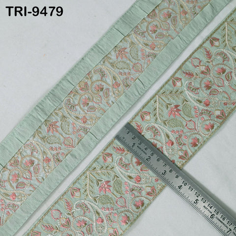 a close-up view of a decorative fabric with a floral pattern, featuring a light green border. A ruler is placed next to the fabric, indicating the size or dimensions of the fabric.