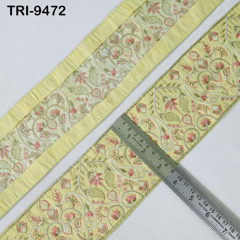 a close-up view of a decorative fabric with a floral pattern, featuring a yellow border. A ruler is placed next to the fabric, indicating its size or dimensions.