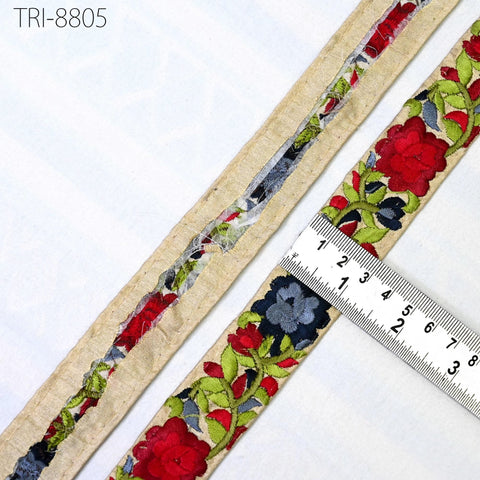 a close-up view of a decorative fabric with a floral pattern, including red and green flowers, and a ruler placed next to it to measure the length of the fabric.
