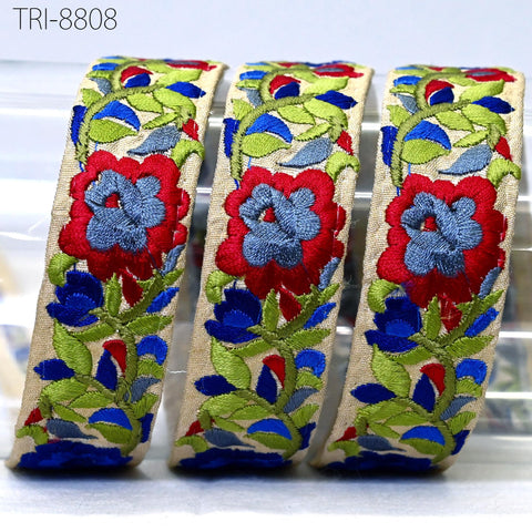 three decorative fabric pieces with floral patterns in red, blue, and green colors. The pieces appear to be made of a light-colored fabric, possibly beige or white, and are arranged in a row.
