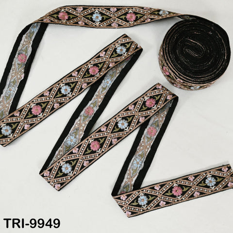 a collection of decorative fabric pieces, including a spool of black thread with a floral pattern and several pieces of fabric with intricate embroidered designs.
