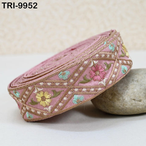 A pink fabric with a floral pattern is displayed on a white surface, with a rock placed next to it.