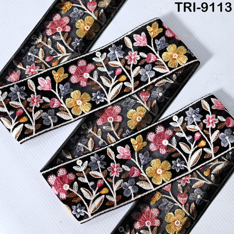 a decorative fabric with a floral pattern in black, yellow, and pink colors. The fabric appears to be a decorative trim or border, with the flowers and leaves intricately embroidered or printed onto it.