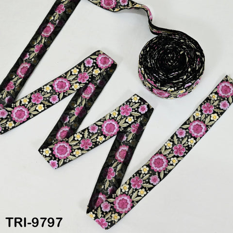 a collection of floral-patterned fabric pieces, including a spool of black and pink floral fabric and several pieces of fabric with a similar floral design.