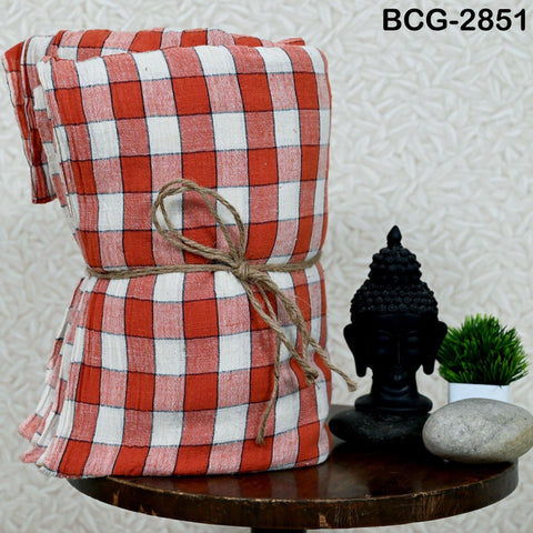 a red and white checkered cloth tied with a twine, placed on a wooden table next to a small black Buddha statue and a potted plant.