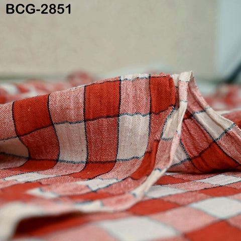 A close-up view of a red and white checkered fabric, with a blurred background.