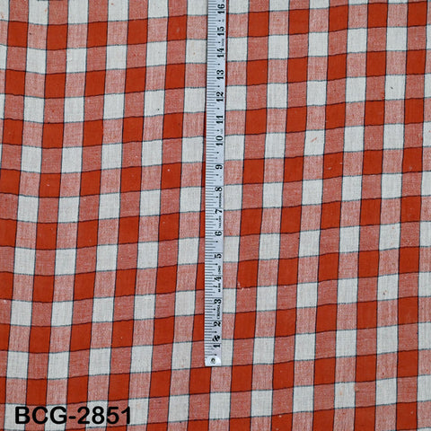 a red and white checkered fabric with a ruler placed vertically on it, indicating the size of the fabric.