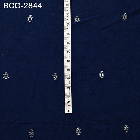 a blue fabric with small white geometric patterns or designs, and a ruler is placed vertically on the fabric to indicate the size.