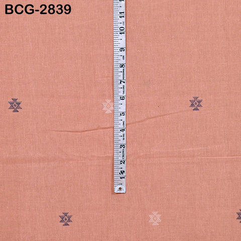 a ruler placed vertically on a peach-colored fabric with small white and blue geometric patterns.
