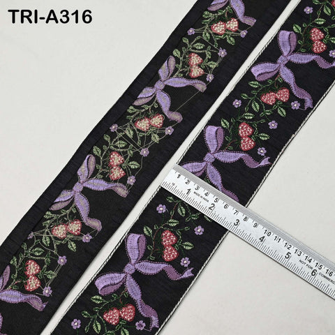 a close-up view of a decorative fabric with a floral pattern and purple bows. A ruler is placed next to the fabric, indicating its size.