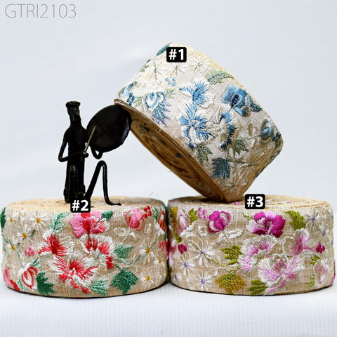 three decorative fabric rolls with floral patterns, each with a different color and design. A small black figurine is placed on top of one of the rolls.