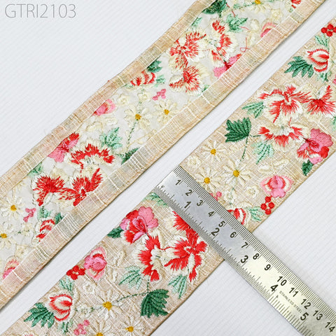 a close-up view of a decorative fabric with a floral pattern, placed next to a ruler for scale.