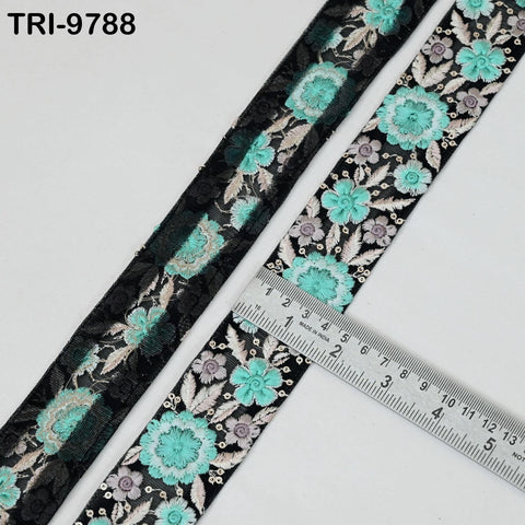two spools of fabric with a floral pattern, one black and one turquoise, placed next to a ruler for size comparison.